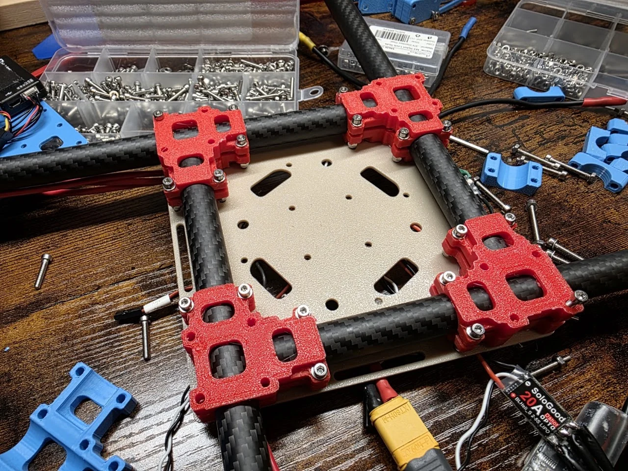 Printed center plates and red mounting components alongside quadcopter arm tubes